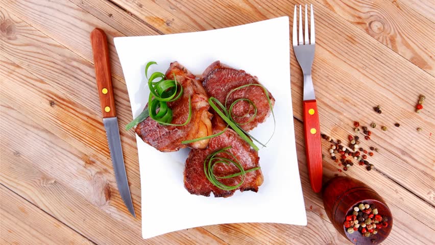 grilled meat beef steaks strips plate with pepper and cutlery over wood table 1920x1080 intro motion slow hidef hd