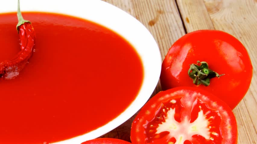diet food : hot tomato vegetable soup with basil thyme and raw tomatoes in white round bowl over red mat on wood table ready to eat 1920x1080 intro motion slow hidef hd