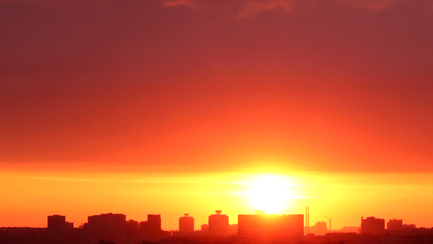 Bright, orange sunrise. The sun appears and disappears in low clouds