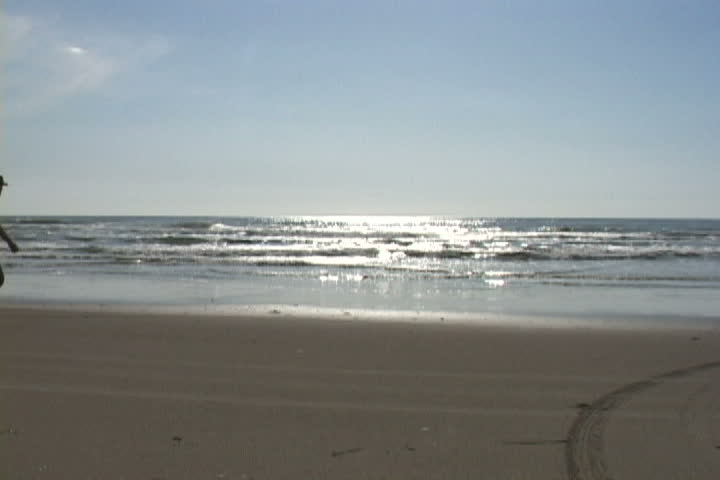 Man walks sandy, ocean shores in Oregon.