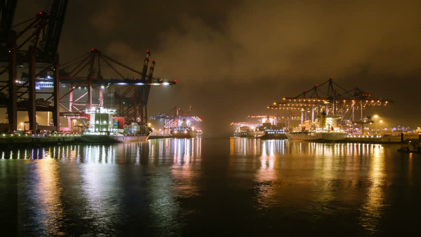 Time lapse of container harbor at night, ships being loaded and unloaded by cranes
