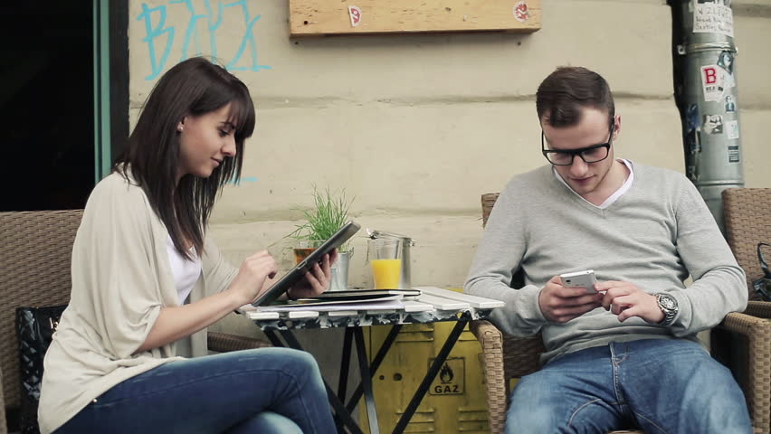 Happy couple with smartphone and tablet in cafe, steadicam shot
