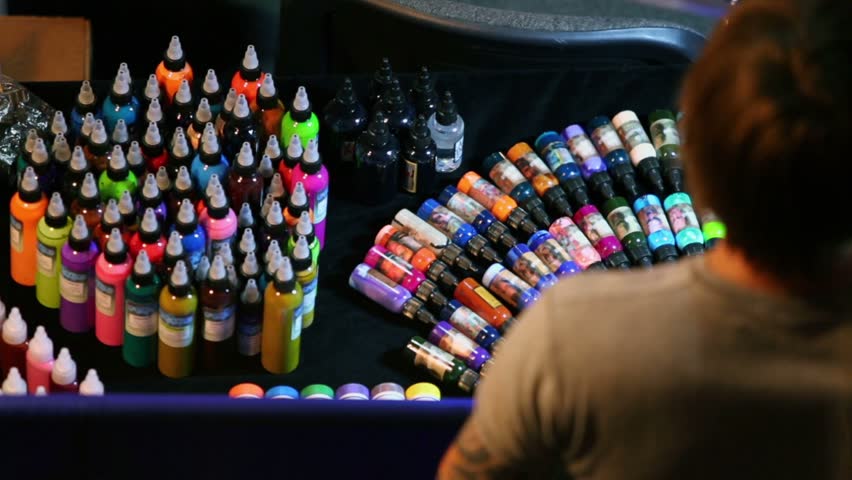 Lot of tubes lay on table with paint of different colors for tattoo
