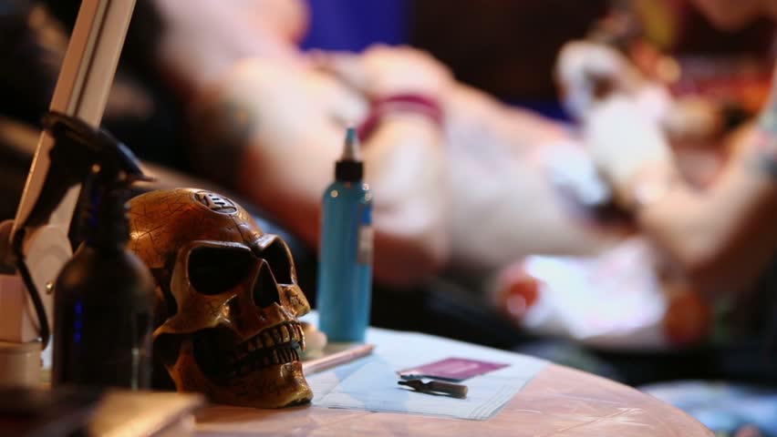 MOSCOW - MAY 20: Tattoo artist works in club ARENA during Moscow International Tattoo Convention V, focus on skull at table on May 20, 2012, Moscow, Russia. Tattoo word taken from Polynesian language