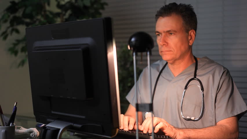 A doctor or surgeon working at his computer late at night.