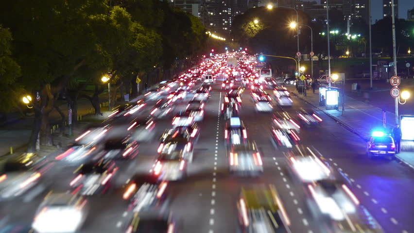 Traffic in the city. Avenue Time-Lapse, Night. Moon going down. Heavy traffic / jam / flowing with blurred motion. Dusk. Dolly out / zoom.