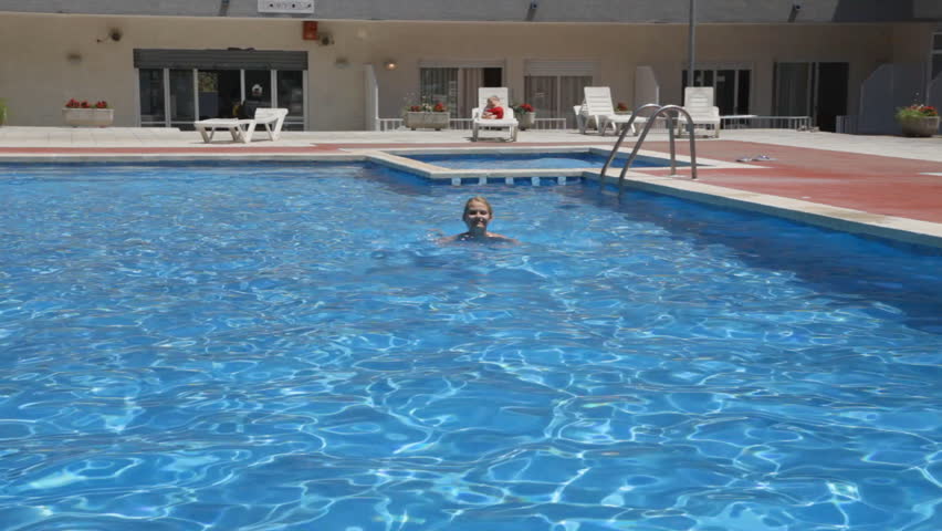young woman swimming in the pool near the hotel