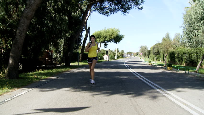 Woman jogging on street slow motion wide shot/Gorgeous female athlete running on street exercizing dolly shot