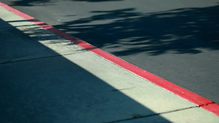 A skateboarder fails down while grinding a curb. Shallow depth of field.