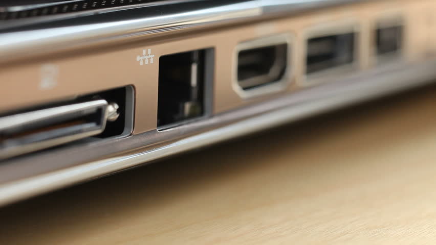 Closeup of ethernet cable being plugged into laptop computer.