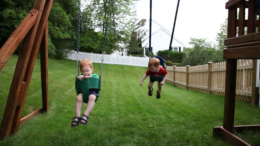 Twin boys on a swing in backyard