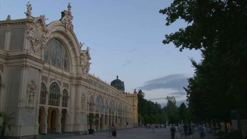 Pseudo-Baroque cast iron unique City Colonnade in Marianske Lazne (West Bohemia, Czech) with walking people and fountain during dusk. Time lapse.