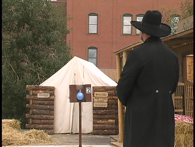 A "gunfighter" in a cowboy shooting fastdraw competition draws, fires, and pops a balloon, in slow motion