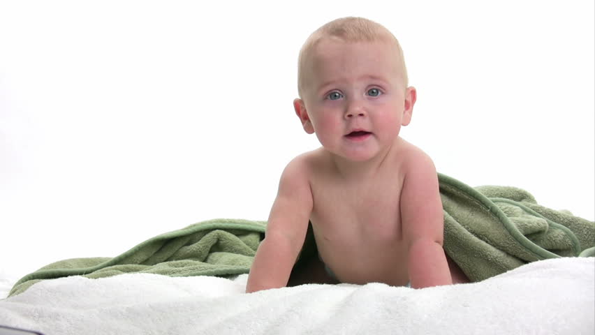 Baby laying on a white towel with a green blanket playing, isolated on white background. hd 1080i