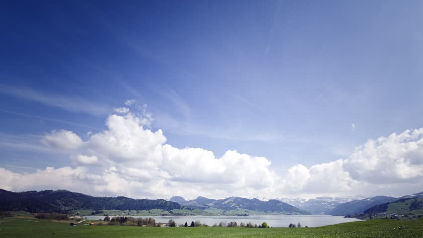 A moving postcard: clouds form above a mountain lake.