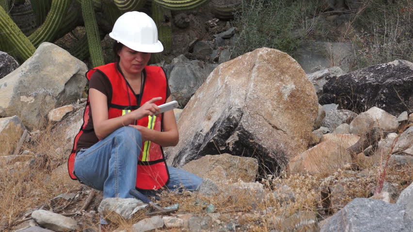 Female Geologist Or Prospector Picks Up A Rock Out In The Field And ...