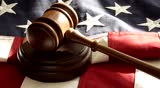 Order In The Court - A Judge says the words and strikes the gavel on the wooden base several times. Background of American flag.