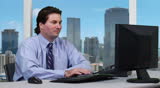 Young business man taking a phone call - office shot overseeing the city skyline