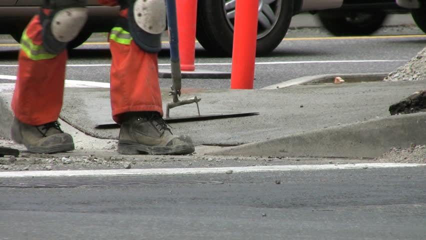 A Construction Worker Smoothing Wet Cement On A New Sidewalk. 