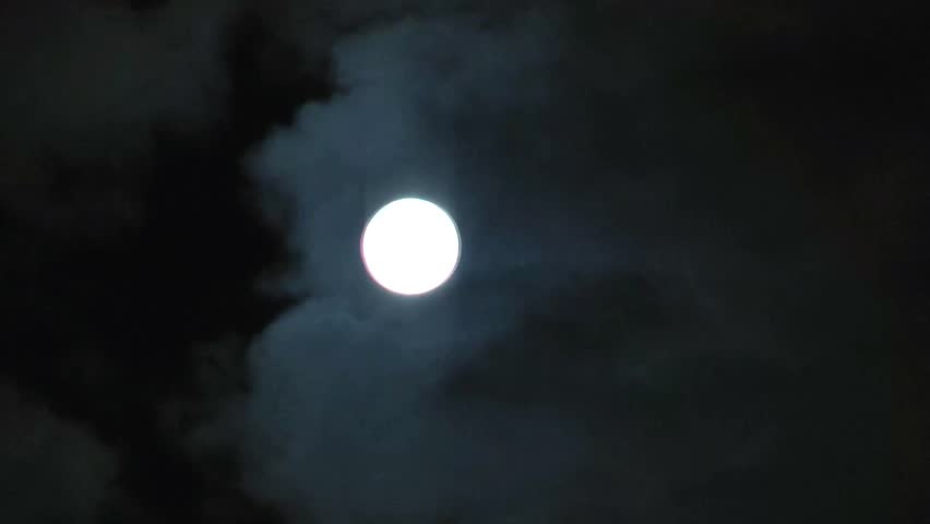 moon in the night sky hides behind quickly running clouds  