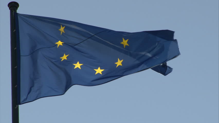 European Union flag is fluttering in the wind. Blue background.