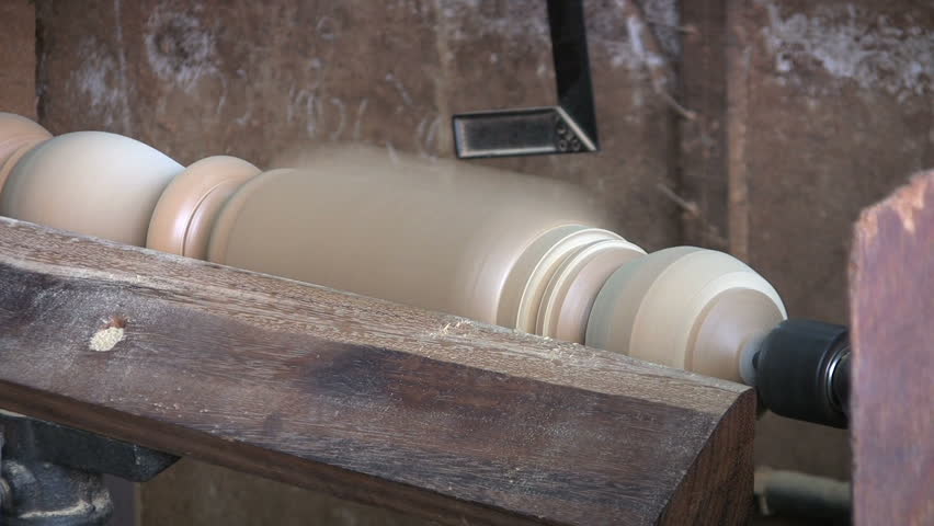 A man shapes a table leg for a kitchen table on his lathe.