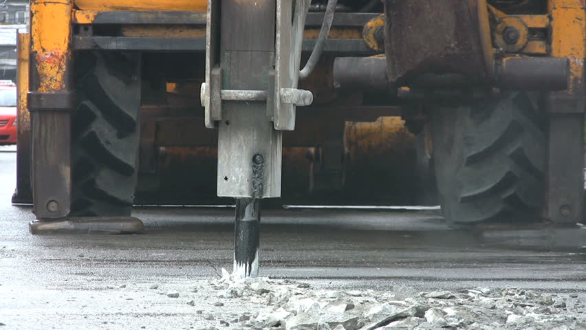 A heavy duty jackhammer begins to bust up the concrete to repair a road in Bangkok, Thailand.