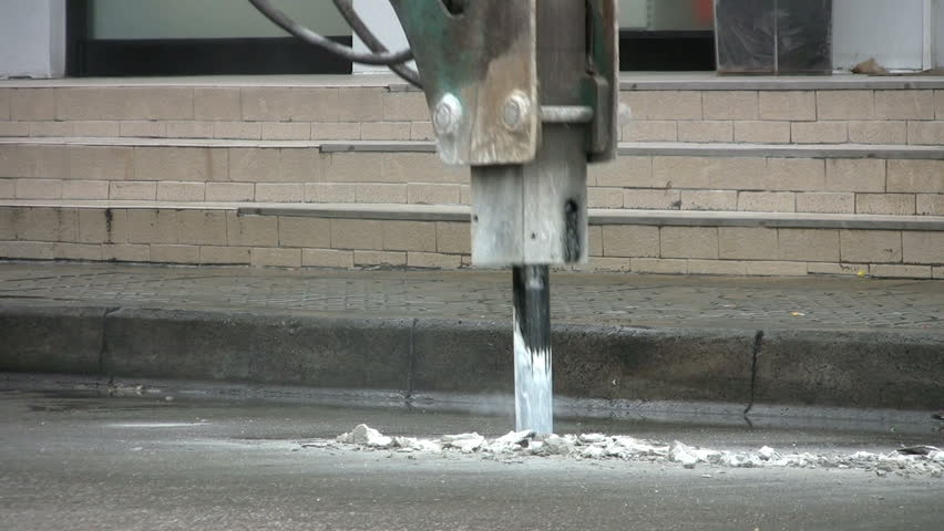 A close up shot of a heavy duty jackhammer beginning to bust up the concrete to repair a road in Bangkok, Thailand.