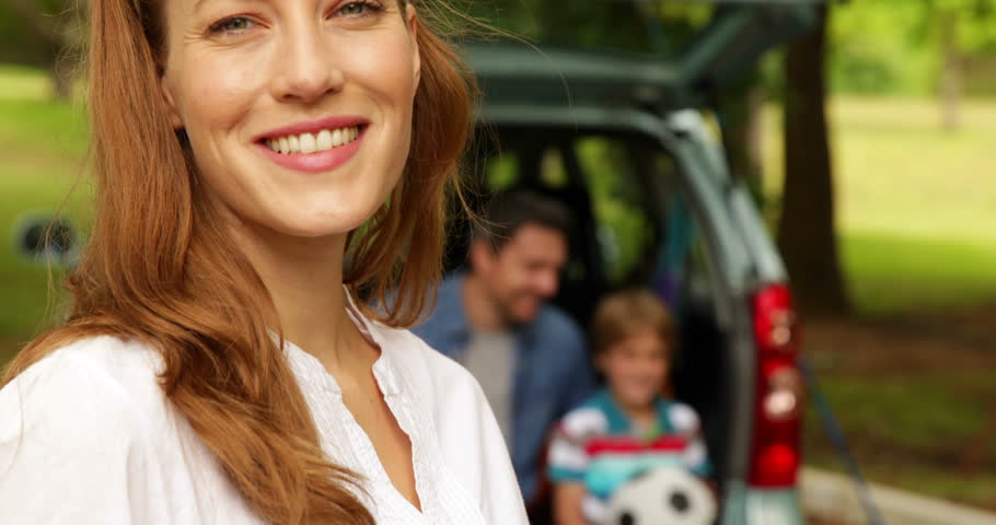 Mother and daughter smiling at camera in front of father and son on a sunny day