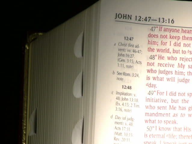 The shot pans across an open Bible as a page is turned.