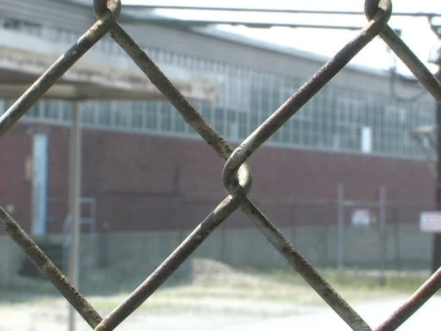 Closed factory behind chain link fence.