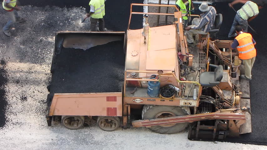 Road construction workers with paving machine