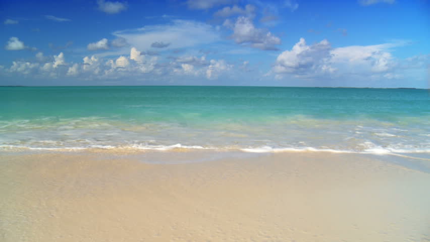 Young female in swimwear running across white sandy beach to swim in aquamarine waters 60 FPS