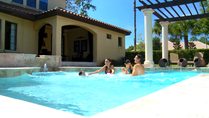 Attractive young caucasian family enjoying  leisure time together in their luxury swimming pool 60 FPS