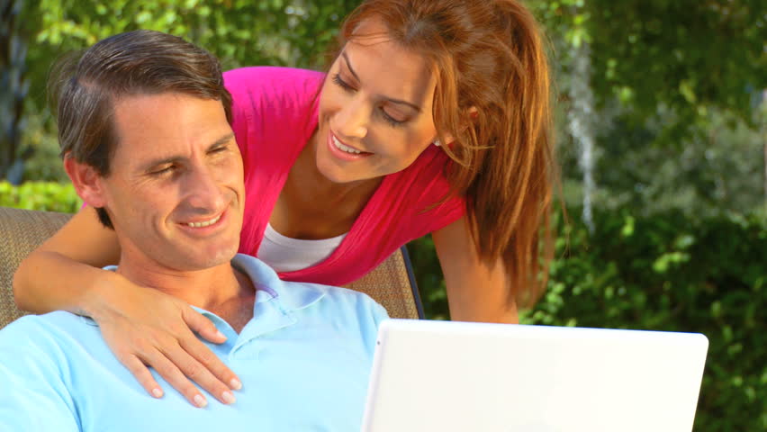 Attractive young heterosexual couple using a laptop outdoors to make future plans