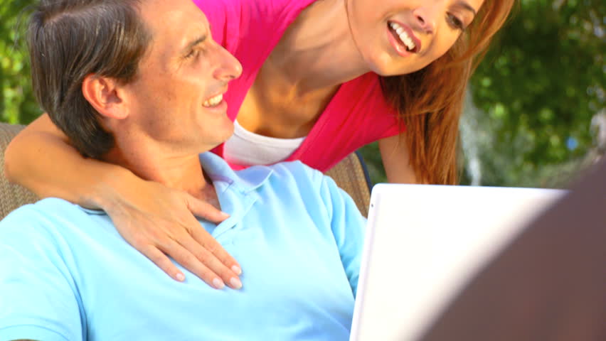 Attractive young heterosexual couple using a laptop outdoors to make future plans