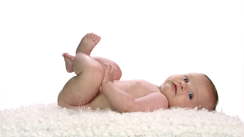 A baby lays on its back on a soft white furry sheet