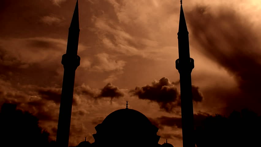 Time lapse clouds flowing past silhouetted twin minaret mosque 4