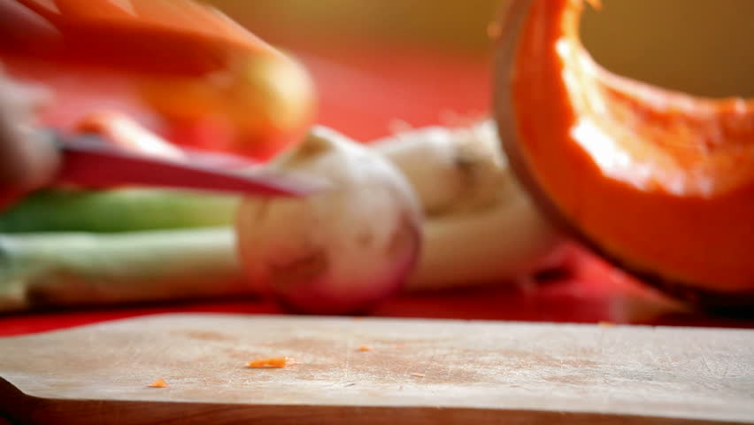  close up on man's hand slicing carrot on cutting board