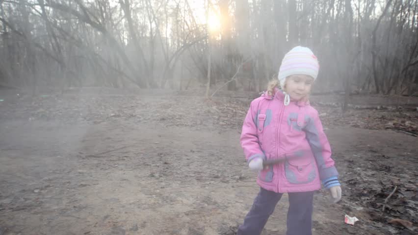 little girl with stick standing near steaming sewer manhole 