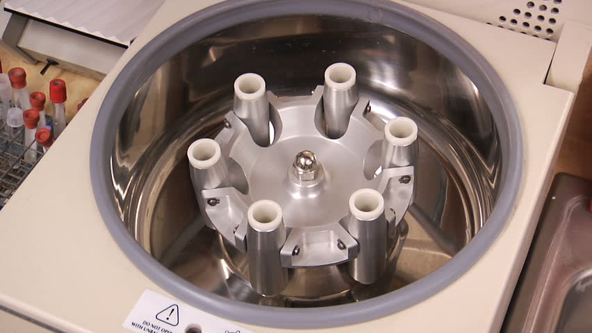 A female scientist loads vials of liquid into a centrifuge in a laboratory.