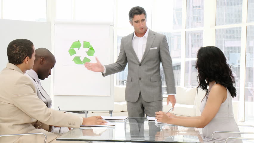 Confident businessman presenting recycling sign in the office