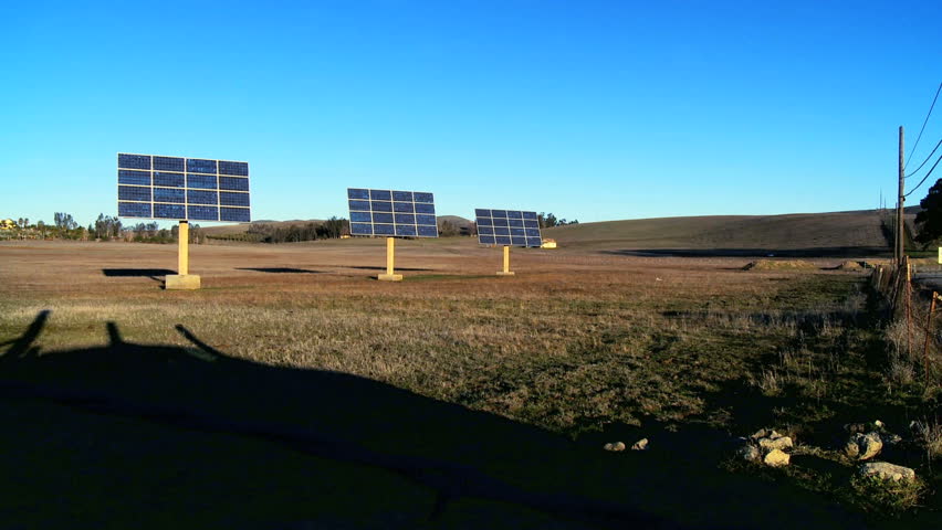 Farms of photovoltaic solar panels producing clean sustainable energy beside highway with traffic pollution