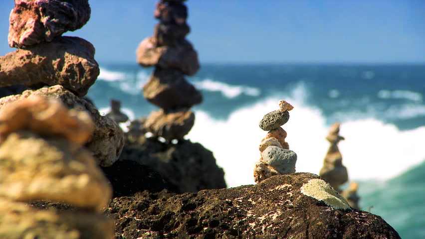 Natural rock stones balanced on shoreline with ocean backdrop