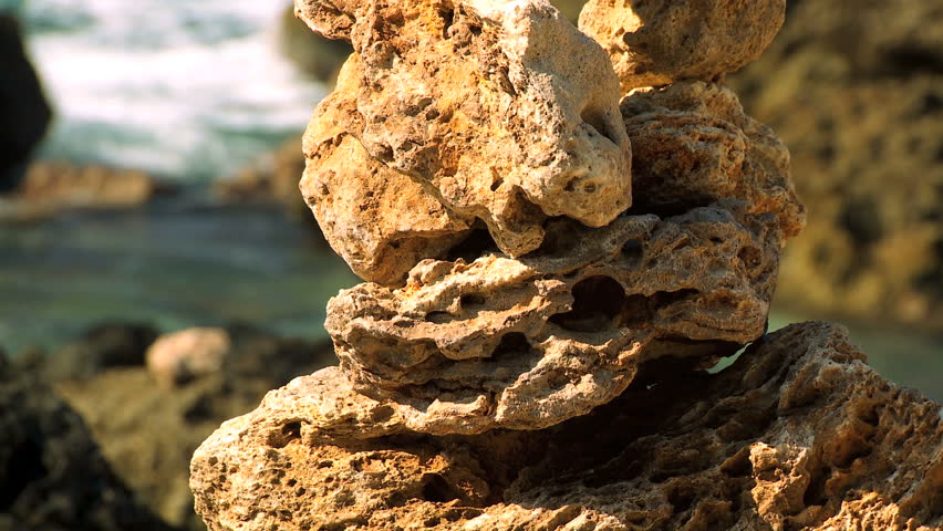 Small rocks symmetrically balanced in peaceful location on shoreline with ocean backdrop