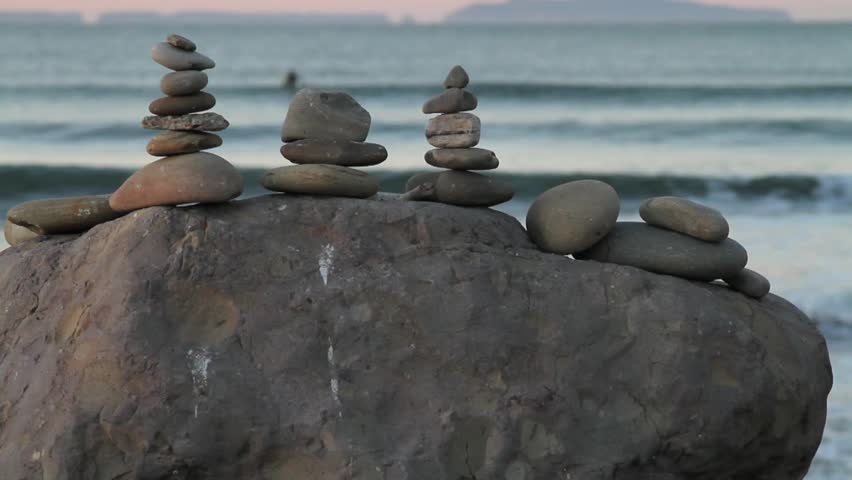 Beach Rocks Balanced, Emerald Sea, Peach Horizon, Islands in background.
