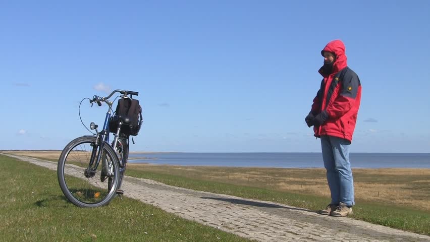 Biker on dike watching for birds