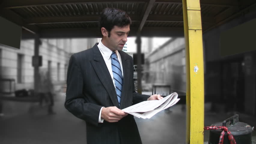 Man reads newspaper. Timelapse commuters in background.