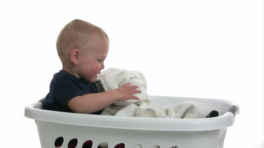 Baby playing with towels in a laundry basket.  Isolated on white.