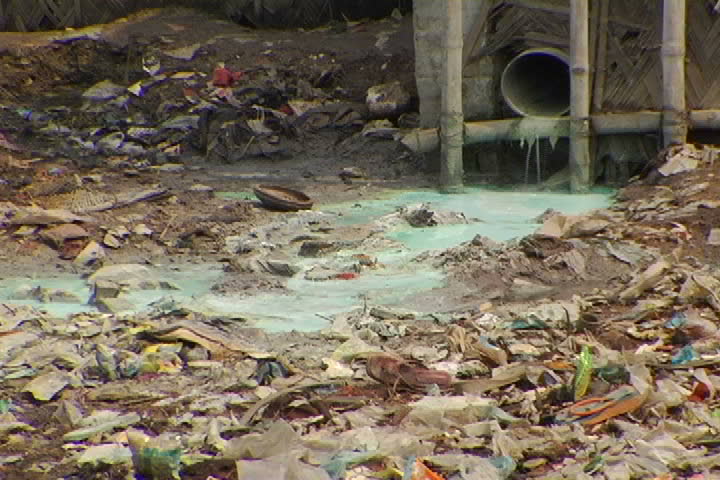 Green, toxic sewage pours out of a drain in a Bangladesh slum.